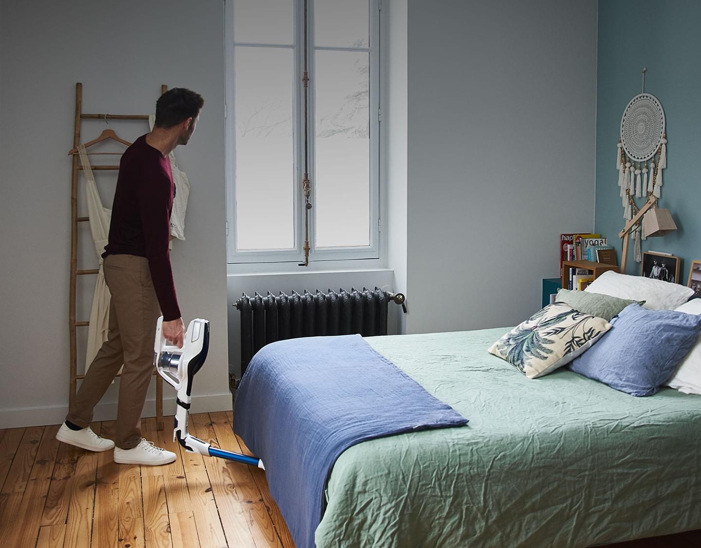 Hombre aspirando debajop de una cama