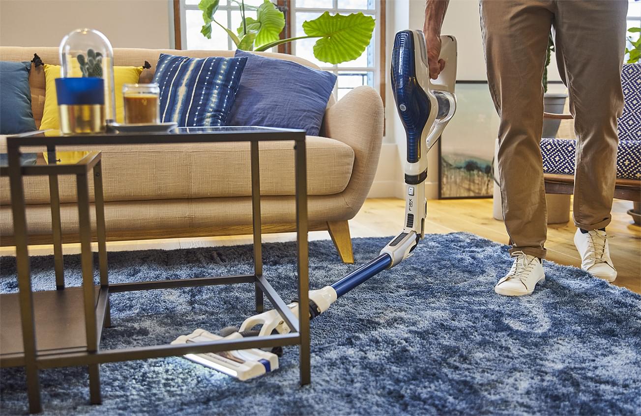 Hombre aspirando debajo de una mesa de hierro forjado